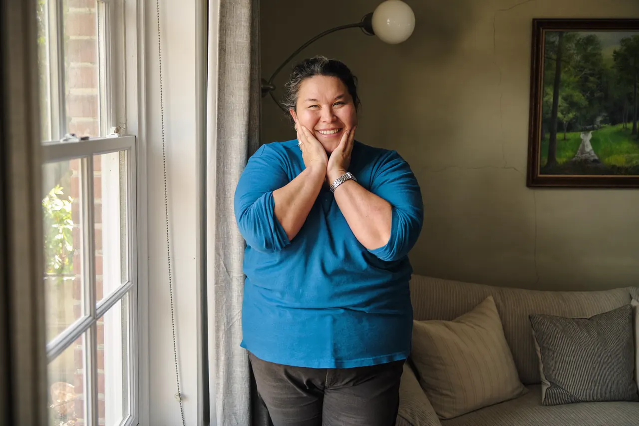 Smiling homeowner beside a bright new bay window in a living room