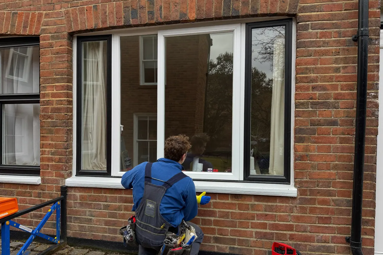 Installer fitting a replacement window to a terraced house front elevation